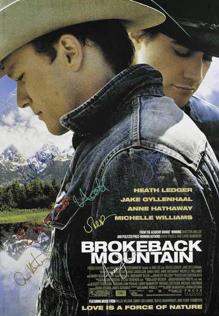 A signed poster for Brokeback Mountain. Heath Ledger and Jake Gyllenhaal are pictured standing in profile. Both men are looking down away from one another. The Rocky Mountains are in the distance.