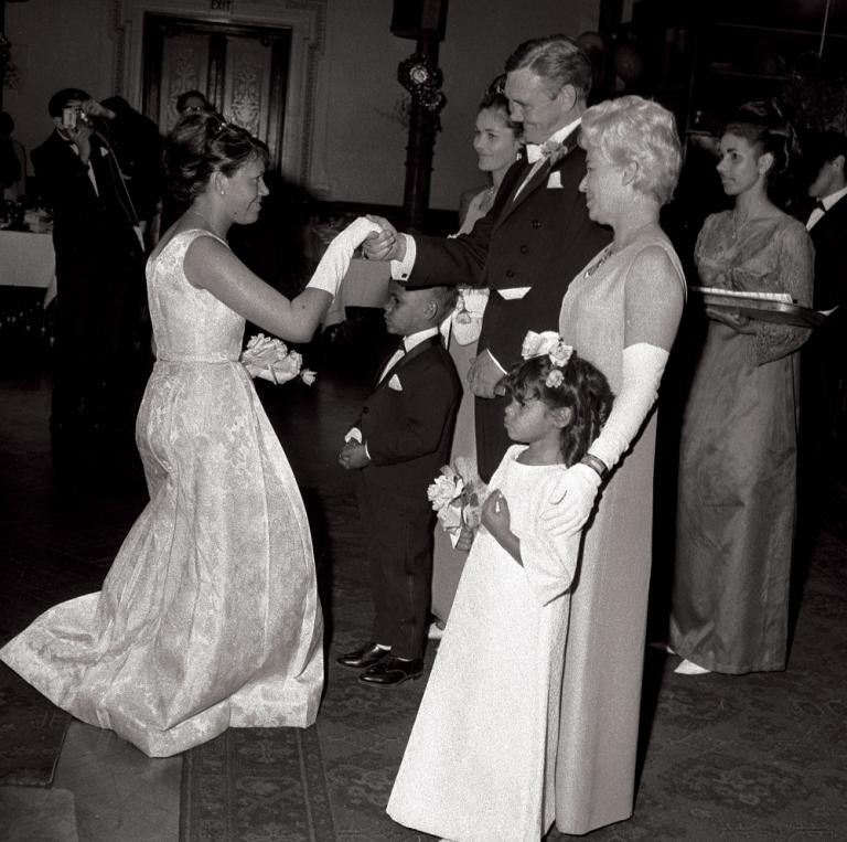 An Aboriginal woman in an evening gown curtseys to Prime Minister Gorton.