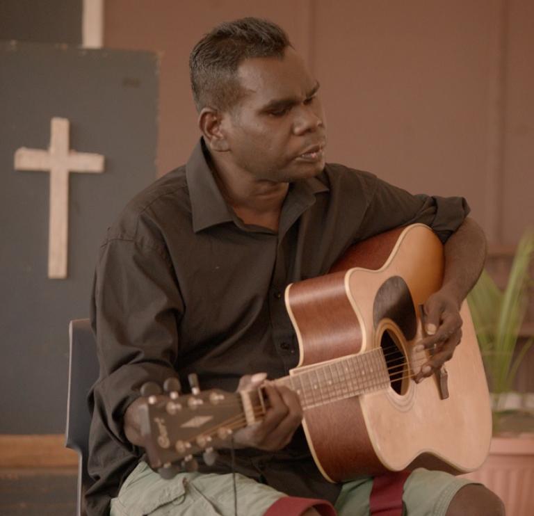 Portrait of Gurrumul playing guitar