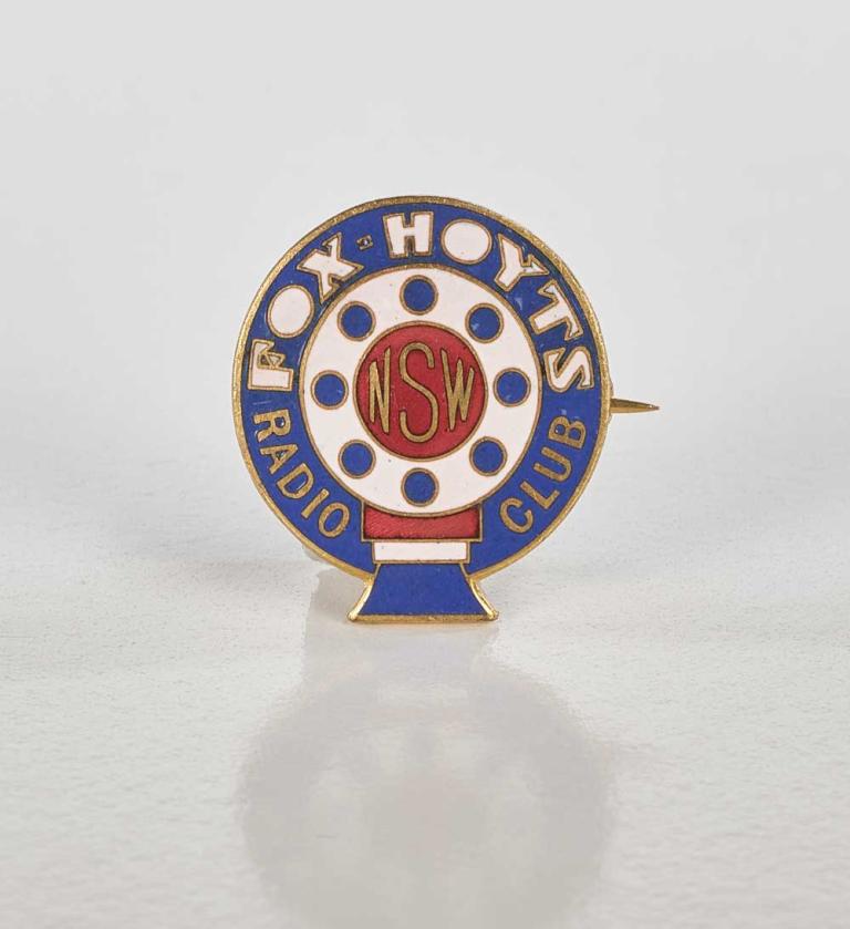 An enamel and metal badge with the words Fox Hoyts printed on it. 