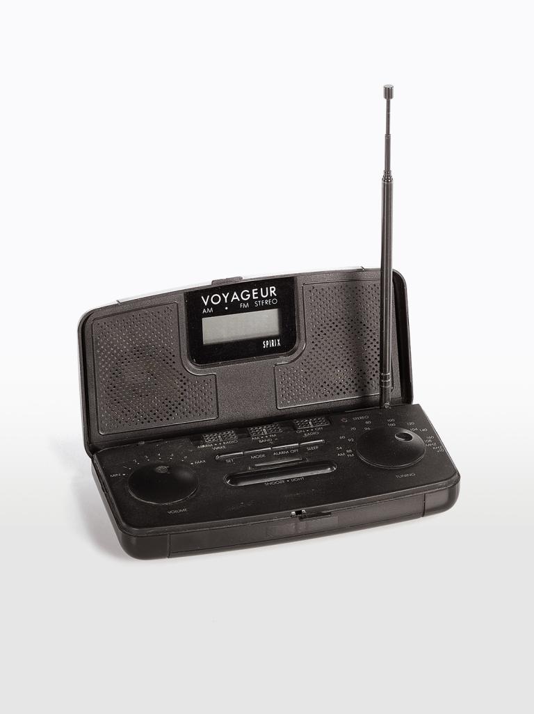 A flat black AM/FM transistor radio in a carry case with an upright aerial.