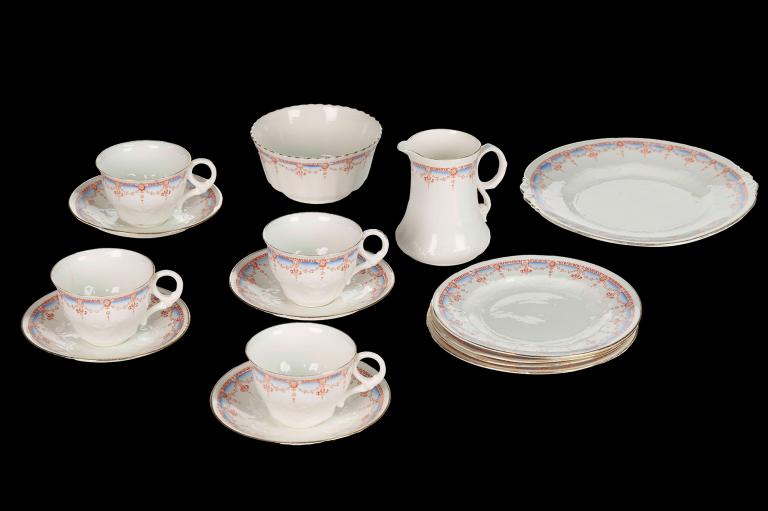 A photo of a white, china tea set with 4 cups and sauces, one sugar bowl, one small milk jug and spare plates. 