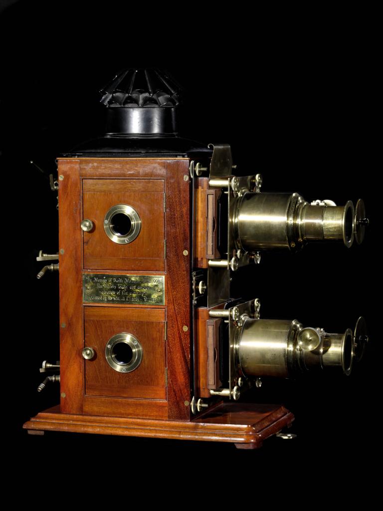 A photo of a lantern projector. It is made from wood and has two lenses on its side.