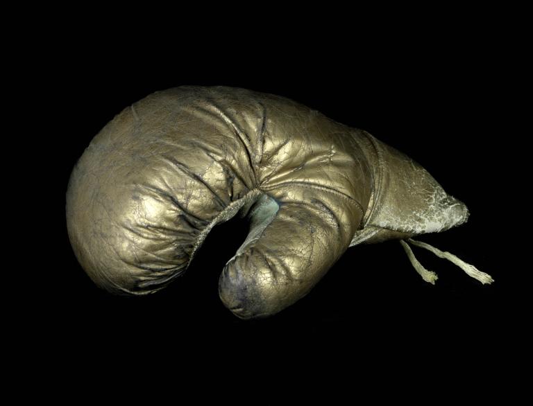 A photo of a golden boxing glove on a black background