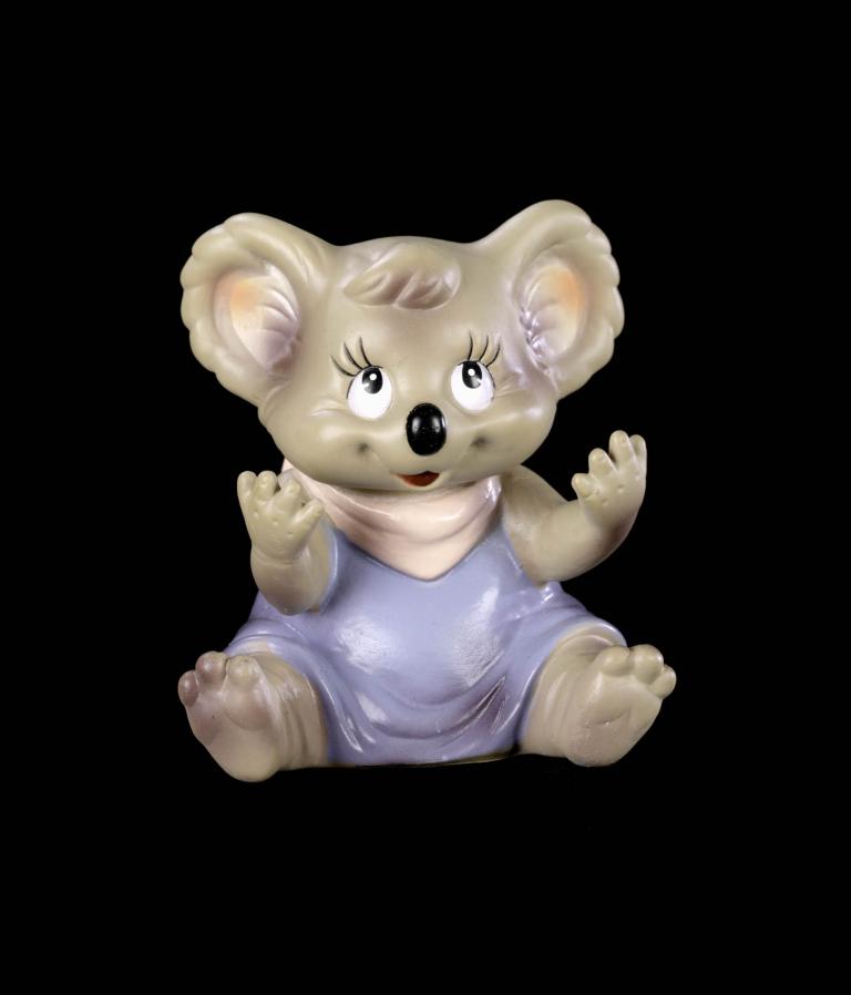 A photo of a Koala hand puppet. It is wearing a blue dress and is looking up. 