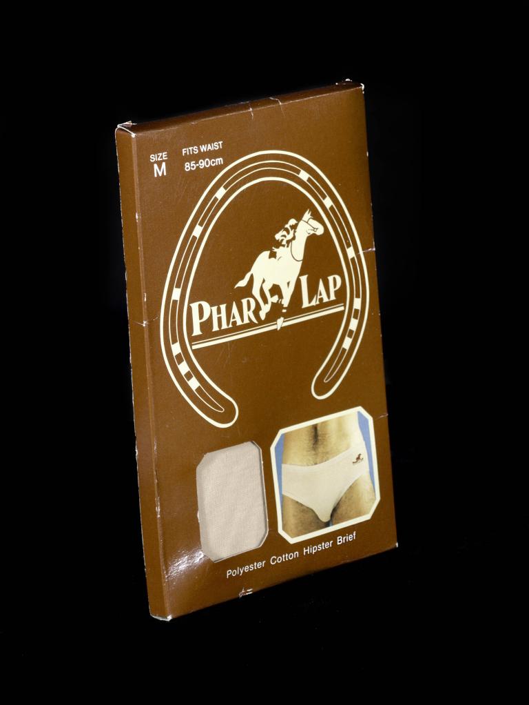 A photo of brown oblong box with the logo for Phar Lap on it. In the small cut away on the box you can see the material for the underwear that it contains. 