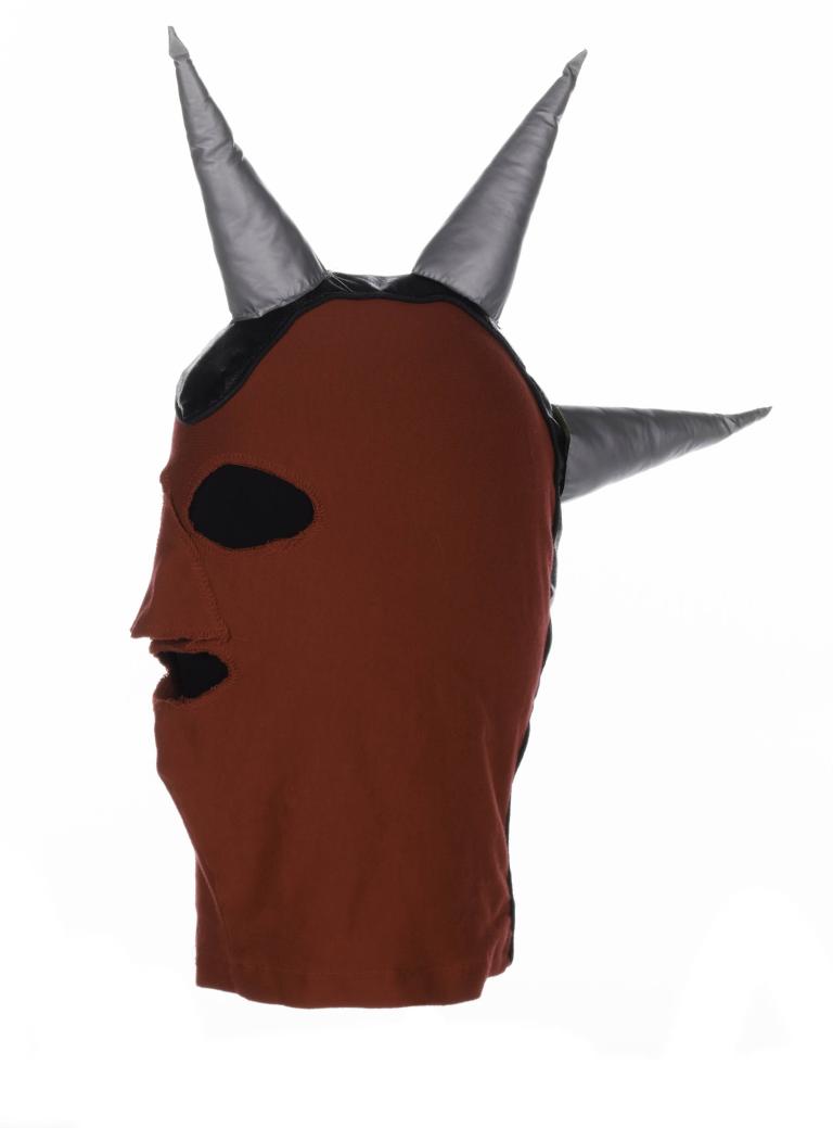 A photo of a red balaclava with three silver spikes coming out from the top of the head and down towards the neck. 