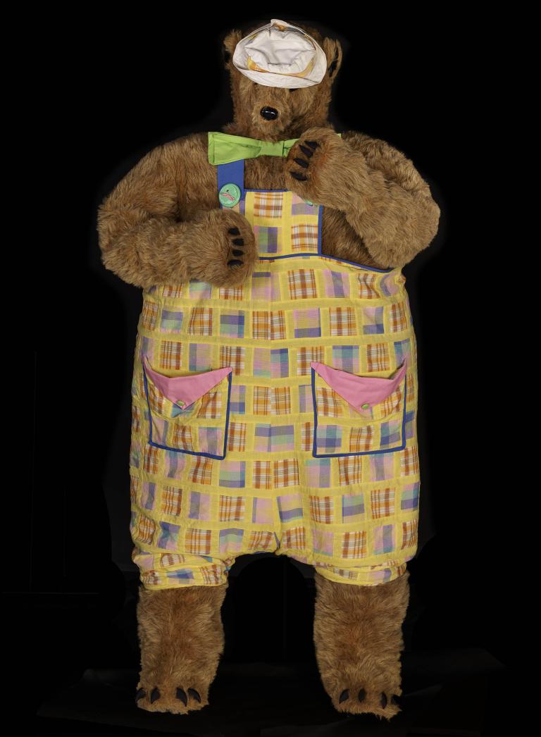 Bear costume with plaid pajamas and green bow tie on black background