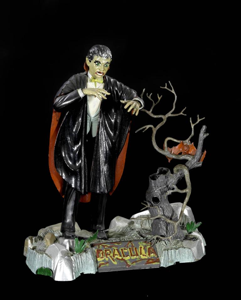 Dracula figurine of Bela Lugosi posed menacingly with cape and tree branch, from the 1960s