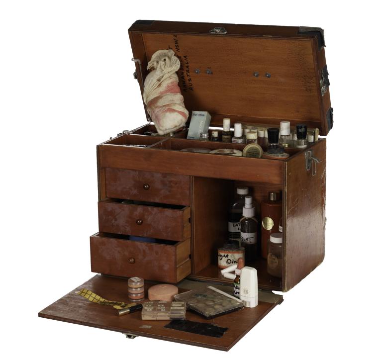 Vintage wooden makeup box with open compartments and various cosmetics