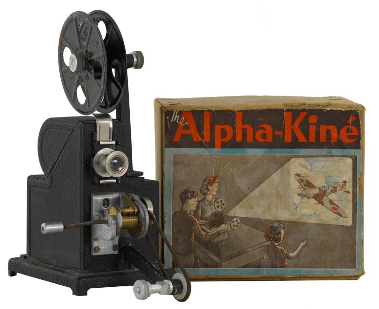 Vintage Alpha-Kiné film projector with illustrated box showing people watching a plane projection.