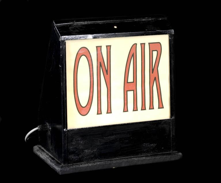 Vintage 'On Air' sign from a radio studio with red lettering on a black background