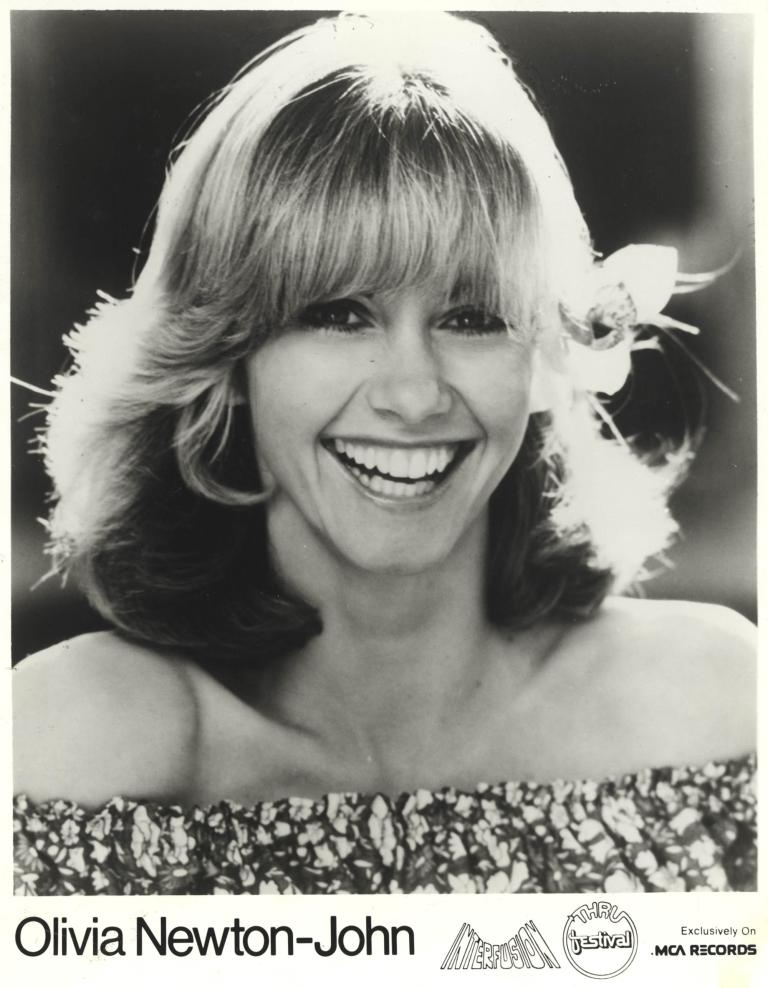 Black and white portrait of Olivia Newton-John smiling, 1980s style