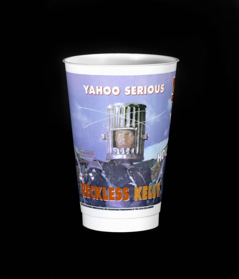 Promotional cup for the 1993 film 'Reckless Kelly' featuring Yahoo Serious wearing a knight's helmet.