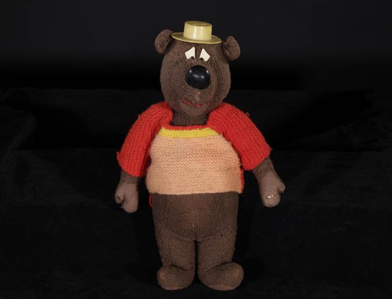 Humphrey B. Bear toy wearing a red and orange sweater with a yellow hat, iconic Australian children's television character.