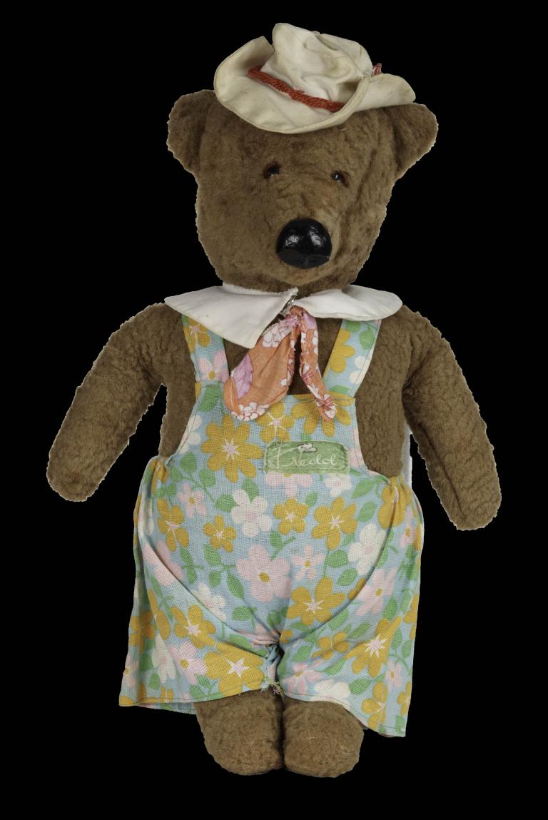 Vintage brown miniature soft toy bear wearing overalls and a hat