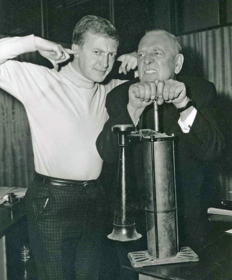 Graham Kennedy and Clifford Nicholls in the early 1950s. Graham is blocking his ears with his fingers while Clifford has his hands on a plunger as if about to make a loud noise.