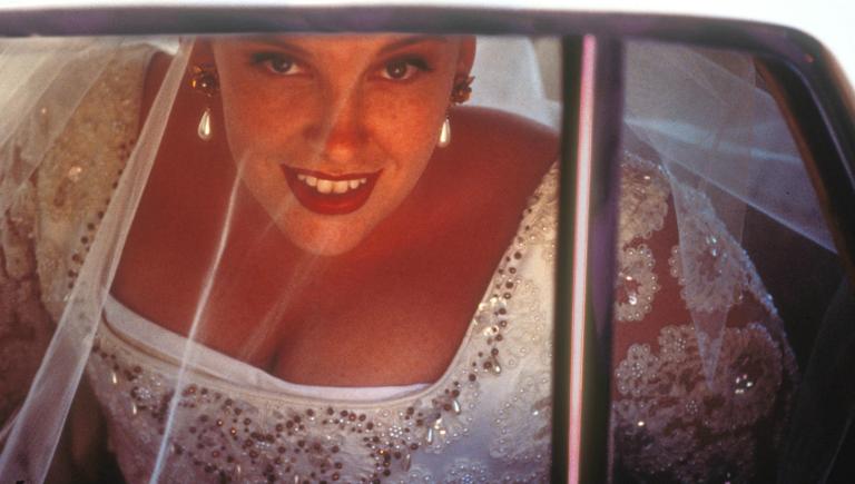 Muriel (Toni Collette) arrives at church in her wedding gown, peering out of car window