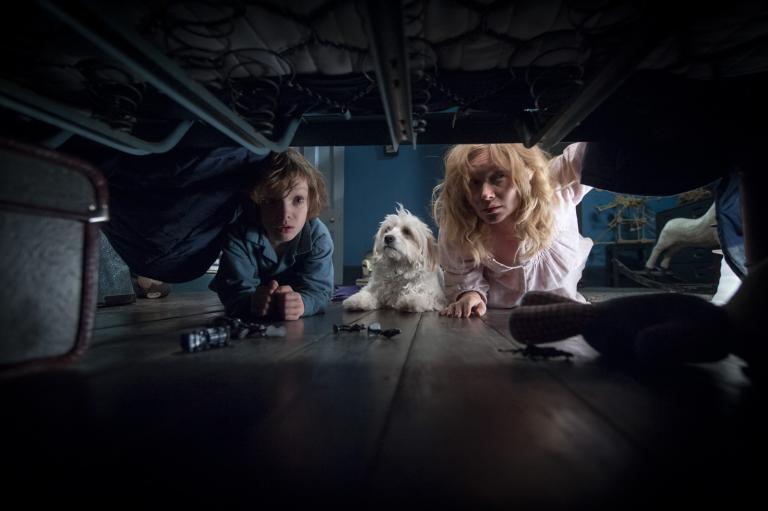 Essie Davis, Noah Wiseman and their dog look under the bed in a scene from the film The Babadook