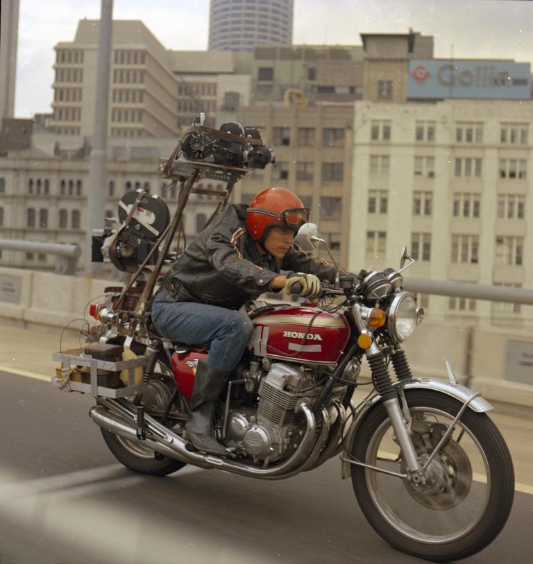 A man rides a motorcycle with a camera mounted on the back.