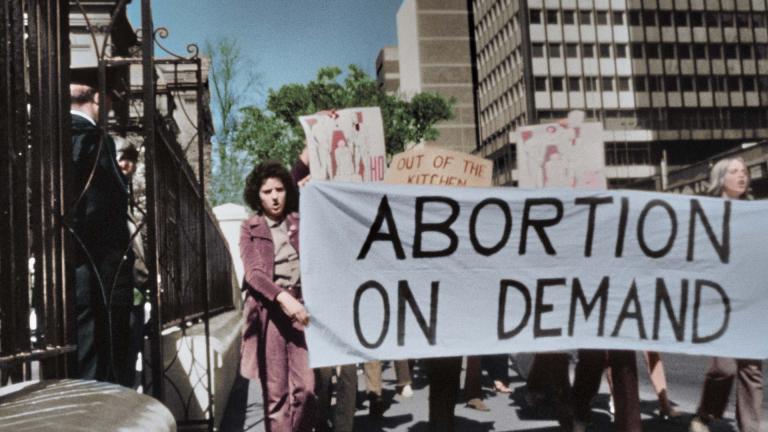 Protesting women on a city street holding up a banner reading 'Abortion on demand'