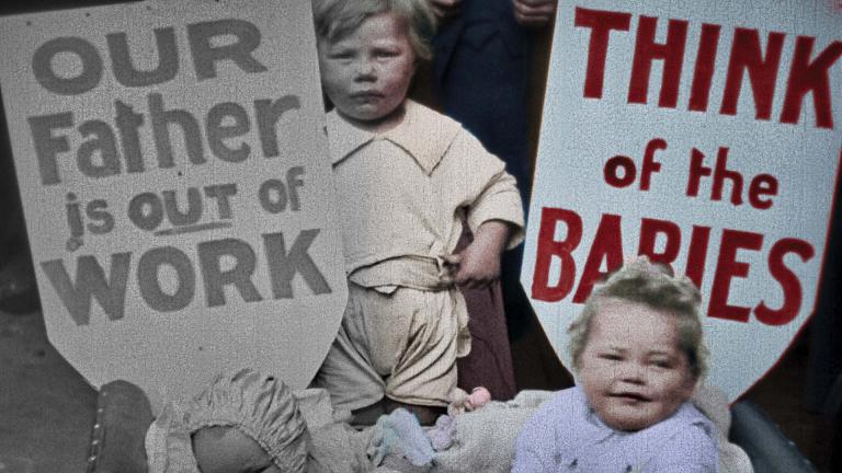 A partially colourised image featuring two young children and banners reading 'Our father is out of work' and 'Think of the babies'