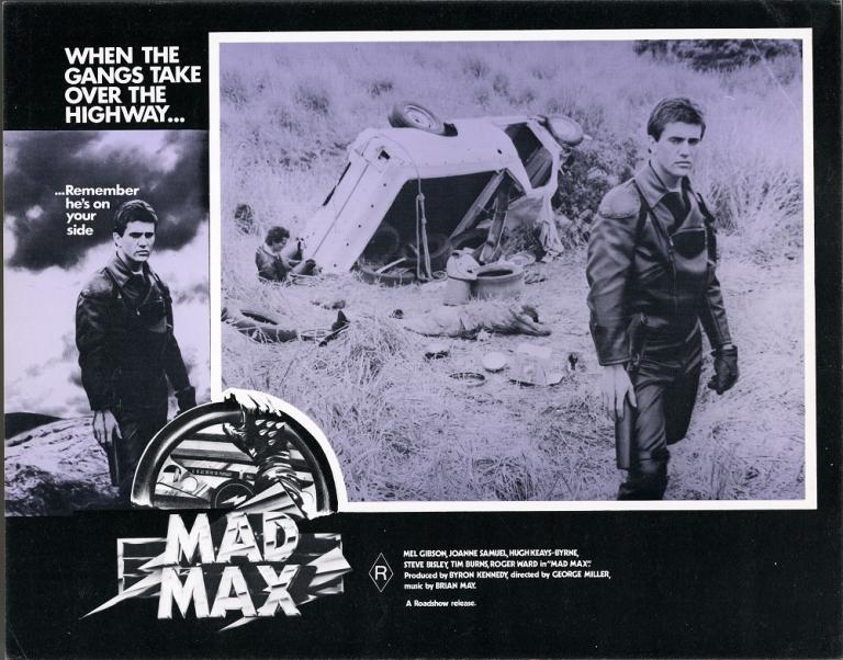 Lobby card for Max Max shows Max (Mel Gibson) next to an overturned car