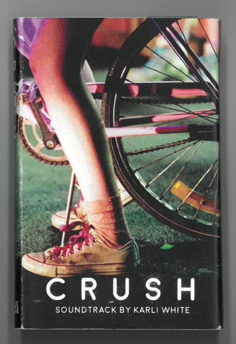 Cassette cover featuring a close up of a woman's leg and foot on a bicycle. Text reads: Crush. Soundtrack by Karli White.