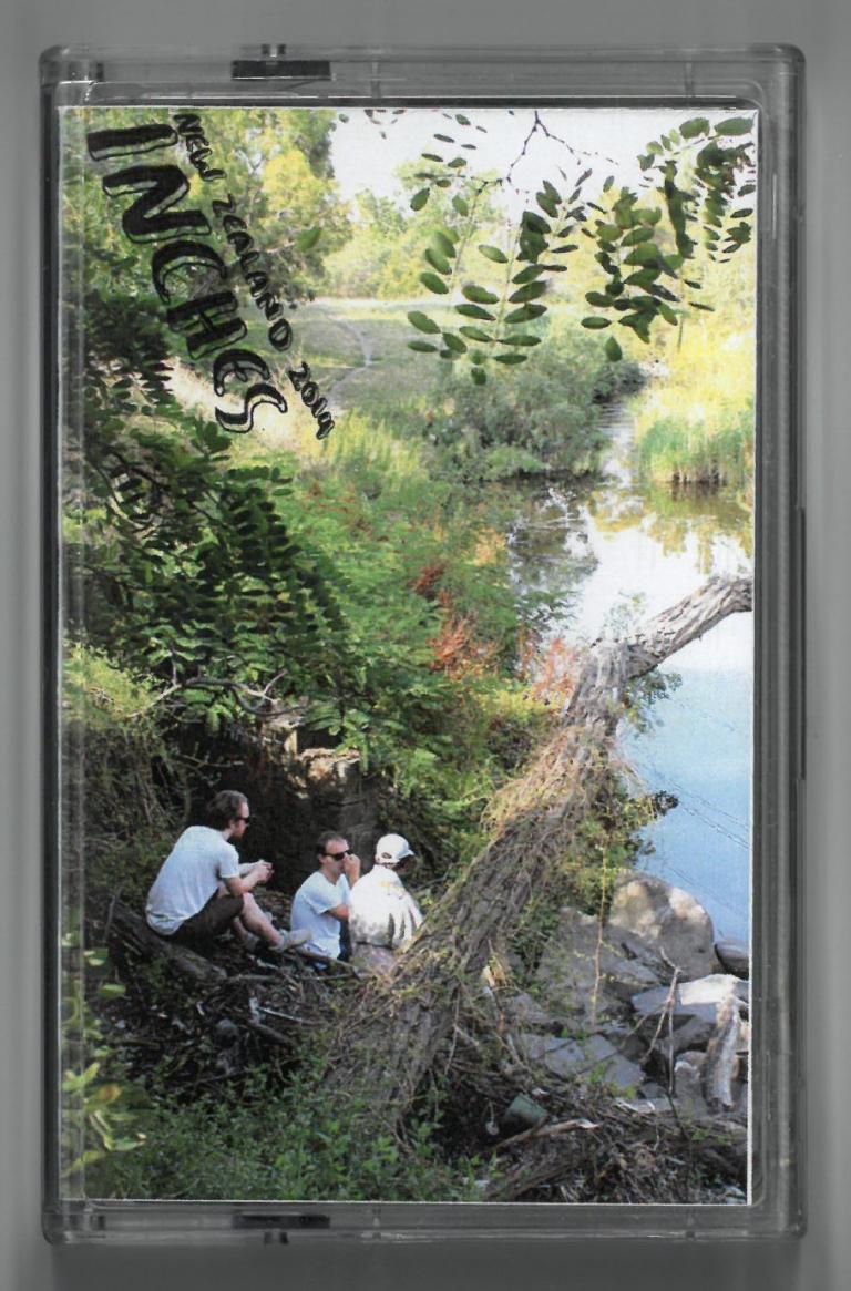 Cassette cover featuring three men by a river. Text reads: New Zealand 2014. Inches.