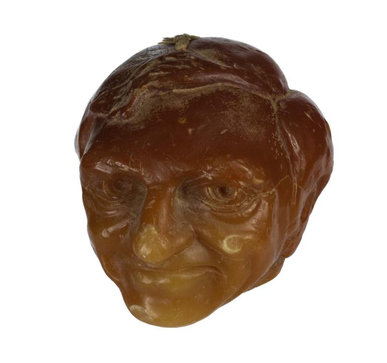 Sculpted orange wax candle of Graham Kennedy's head.