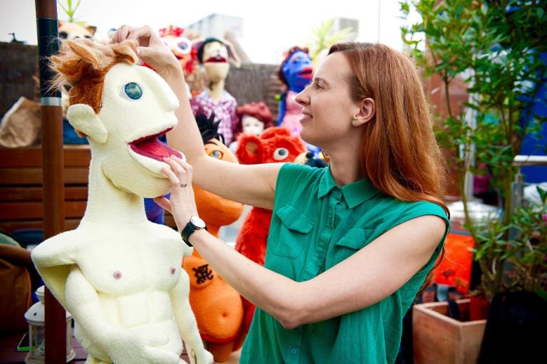 A women examines a lifesize puppet in an open air market.