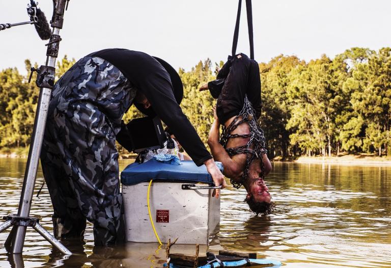 Production shot of a man suspended over a river 