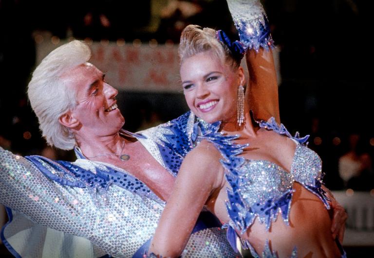 Scene from Strictly Ballroom showing Ken Railings (John Hannan) and Tina Sparkle (Sonia Kruger) in a dance pose wearing matching sequinned outfits.