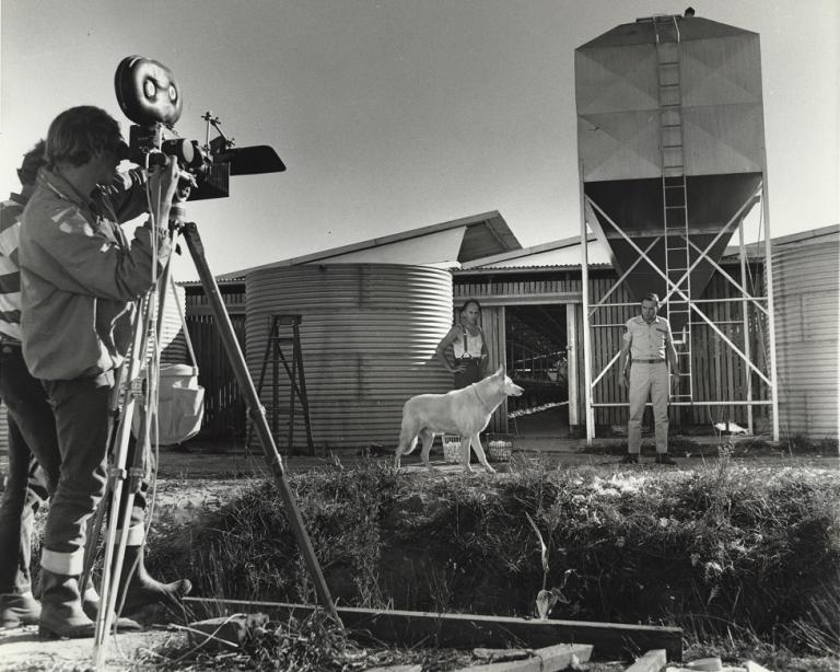 Crew filming Ed Deveraux and John Unicombe on the set of Skippy with a dog.