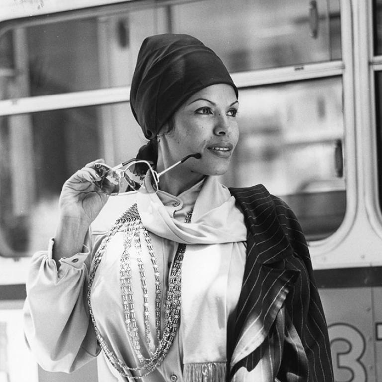 Black and white image of Wilma Reading wearing a scarf and holding a pair of sunglasses