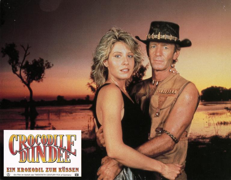 Lobby card depicting Linda Kozlowski as Sue Charlton and Paul Hogan's Mick 'Crocodile’ Dundee looking at the camera