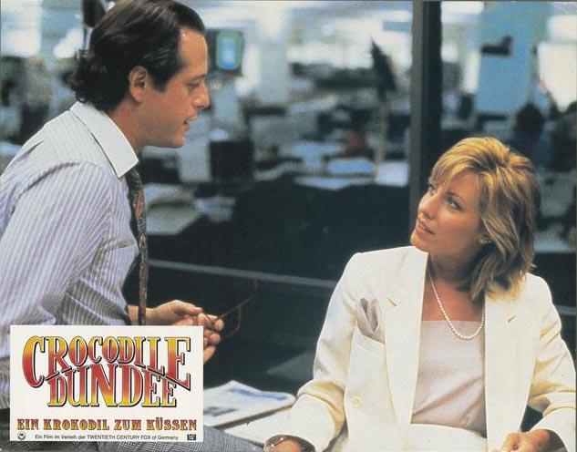 Lobby card depicting Sue Charlton (Linda Kozlowski) speaking with her newspaper editor beau Richard Mason (Mark Blum)