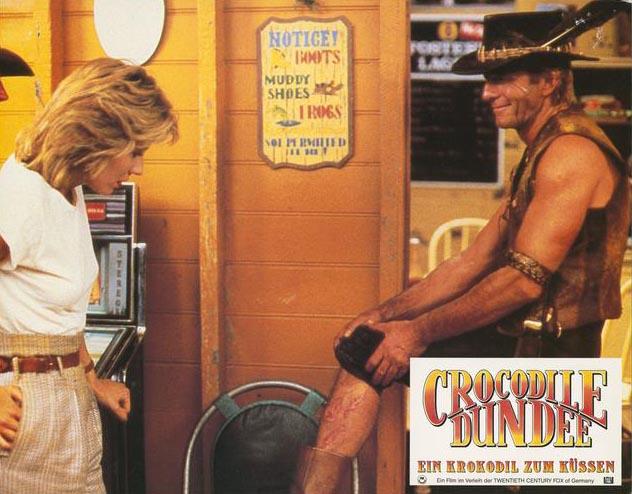 Crocodile bite scar Lobby card depicting Mick Dundee showing off his crocodile bite scar to Sue Charlton.