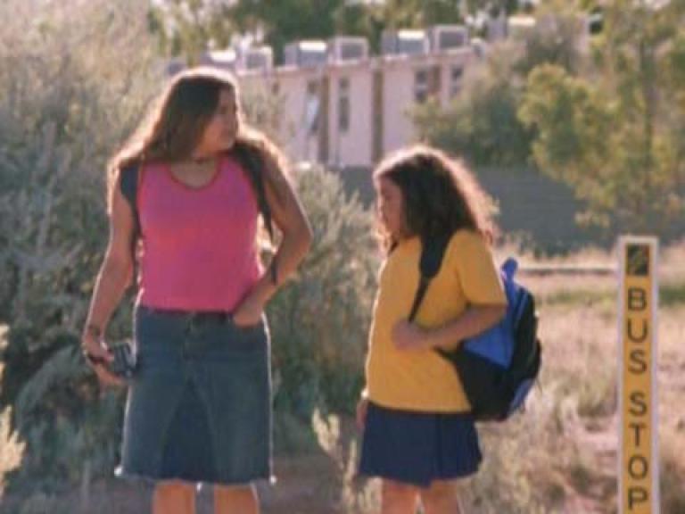Two sisters walk to the bus stop on the way to school