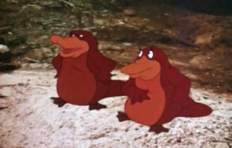 Two animated platypuses standing on a rock in front of a stream in a still from the film Dot and the Kangaroo (1977).
