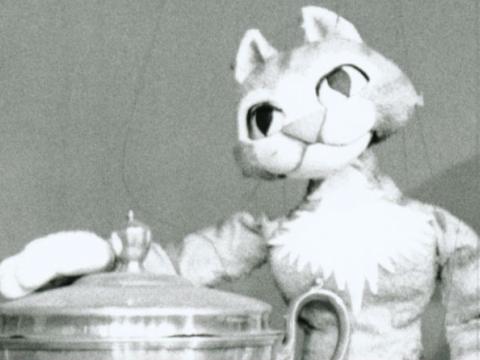 Amanda the Cat puppet leaning on a trophy.