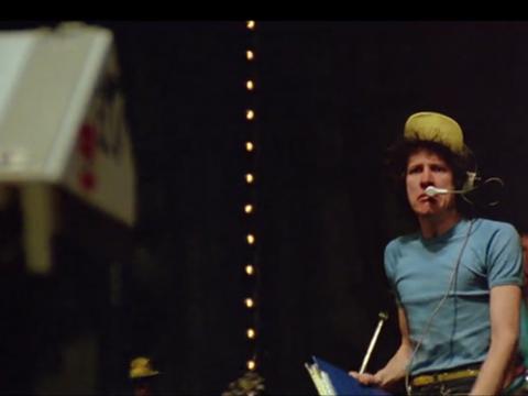 Geoffrey Rush, looking angry and wearing a headset microphone on the stage of the Sydney Opera House