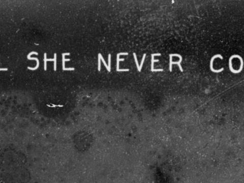 Cropped section of glass slide image that reads 'Will she never come?'