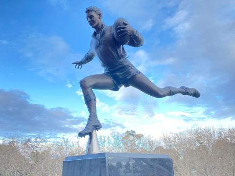 Statue of a man playing Aussie Rules football.