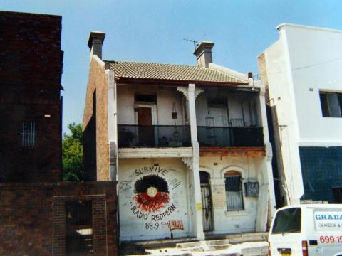 A terrace house with an Aboriginal flag painted on the front wall above the words Radio Redfern.