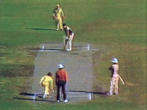 Batsmen, a bowler, umpire and wicketkeeper standing in position on a cricket pitch.