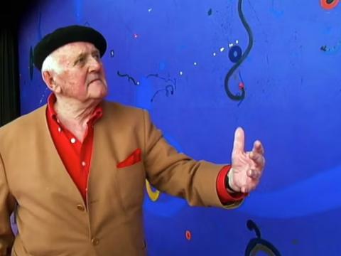 Artist John Olsen standing in front of his mural at the Sydney Opera House