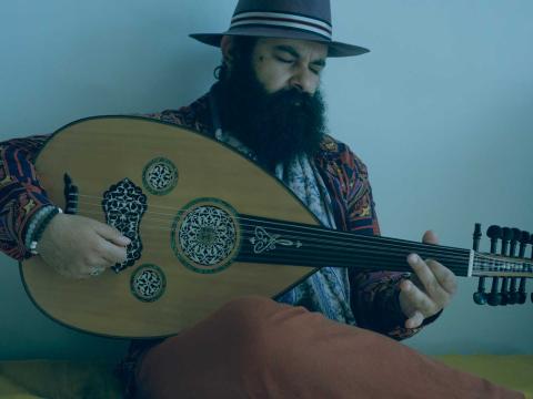 A man wearing a hat and playing a mandolin