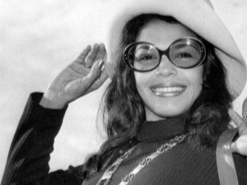 Close up of singer Wilma Reading, c1960s. She's wearing a floppy hat and large sunglasses and smiling broadly at the camera.