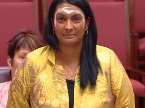 Senator Nova Peris with ochre painted on her forehead and around her eyes giving her inaugural speech to Parliament